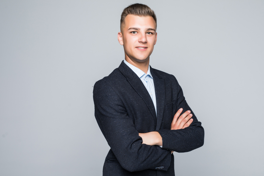 handsome-young-man-student-businessman-jacket-holds-his-arms-crossed-isolated-light-grey-wall
